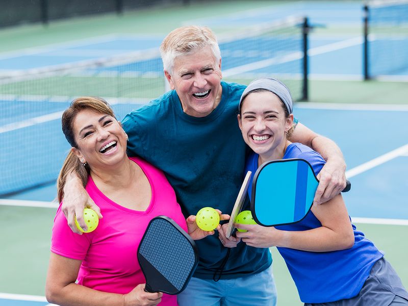 family smiling while playing pickleball
