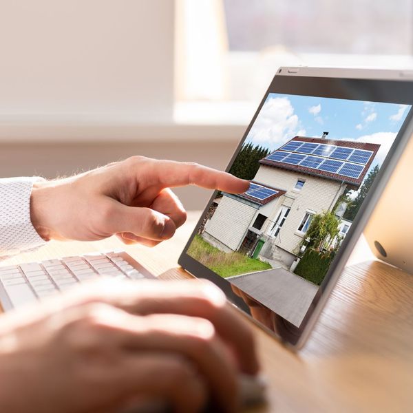 Person pointing to a picture of a home on a laptop screen. 