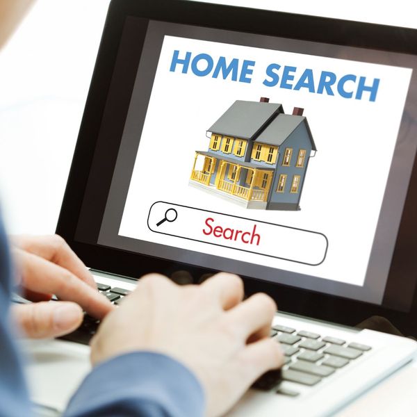 person typing into a laptop with a screen that says "home search"