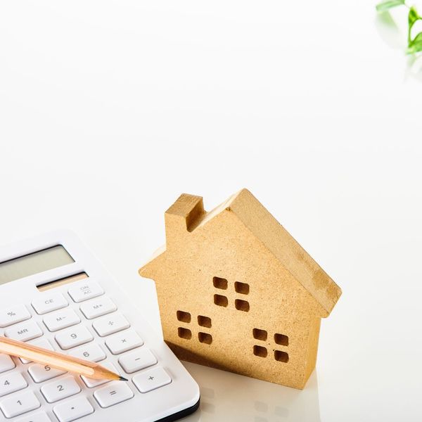 wooden home model with a calculator next to it.
