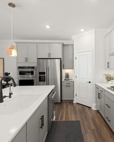 A kitchen with white countertops and grey cabinets