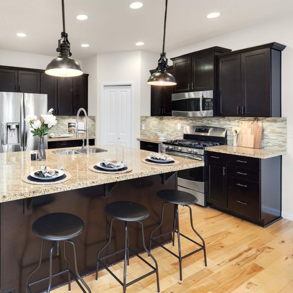 A kitchen with dark wood cabinets and granite countertops, with a kitchen island in the middle of the room