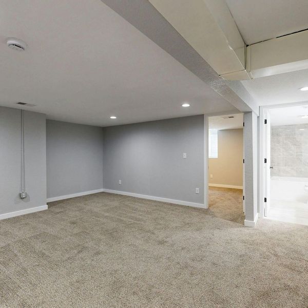 A finished basement with clean carpets and light grey walls