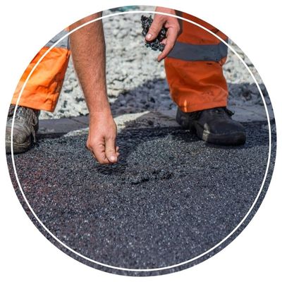 Worker examining fresh asphalt for consistency