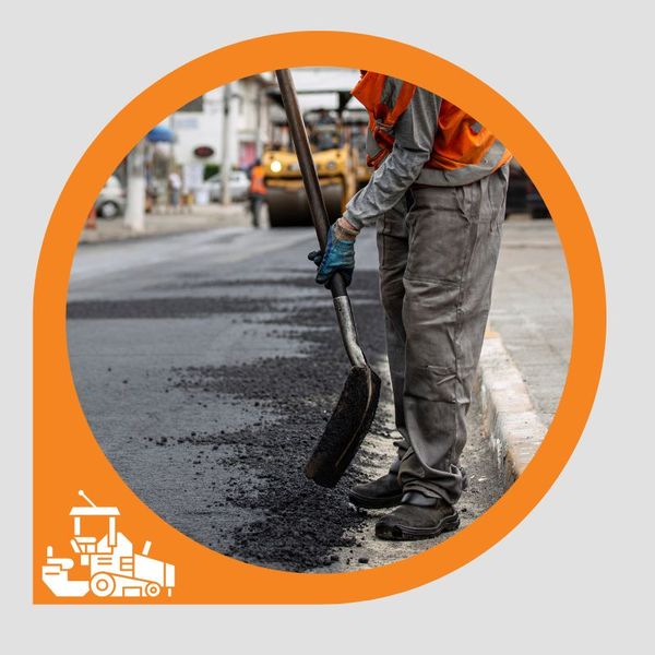 A worker uses a shovel to do some asphalt patching on a road