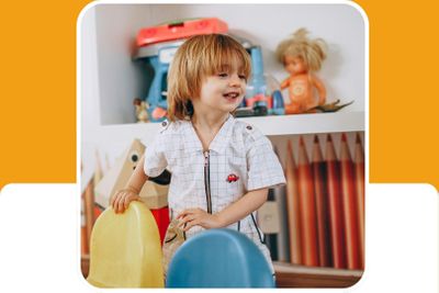 boy in preschool classroom stands behind colorful kids chairs 