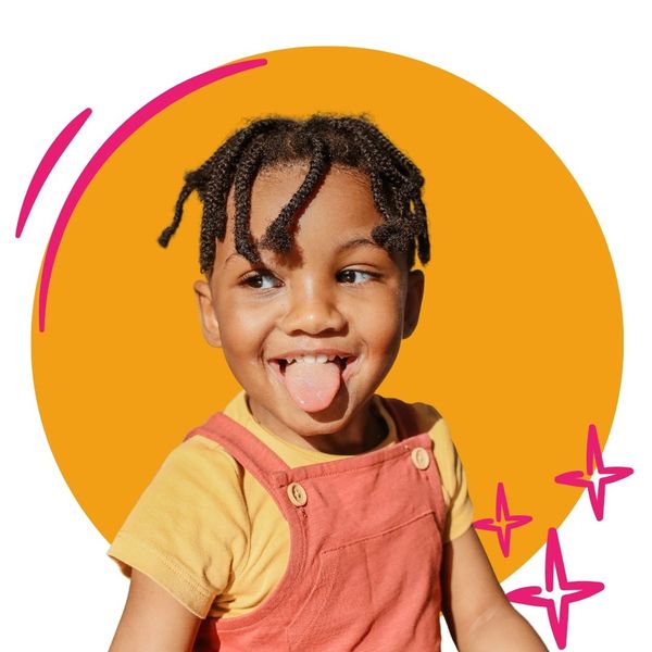 toddler wearing overalls sticks tongue out 