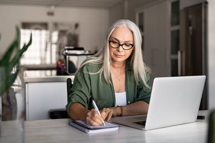 Person taking notes and using a laptop