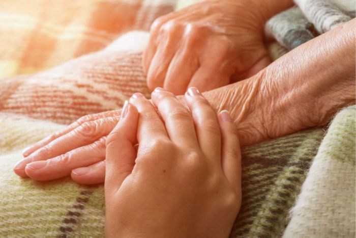 Person comfortingly touching the hand of an older person