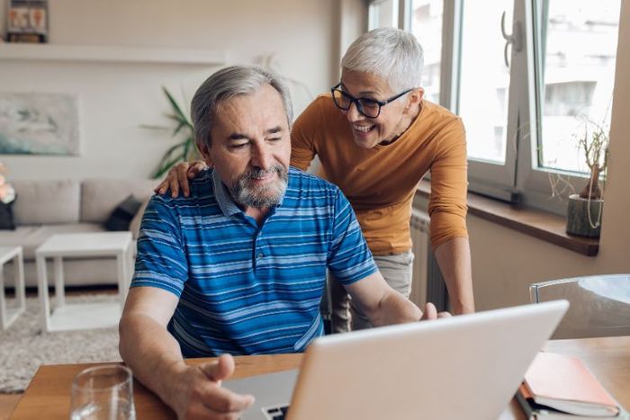 A couple smiling and looking at something on a laptop together