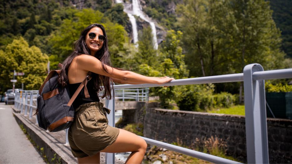 Happy young woman next to waterfall