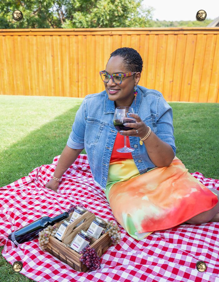 Chef Lorious enjoying wine on a picnic blanket with a box of Jam Vino