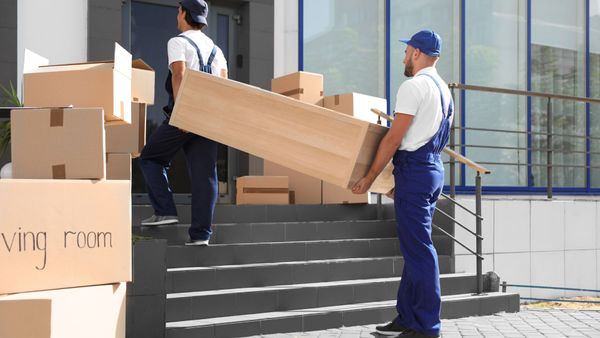 Movers carrying dresser up front porch