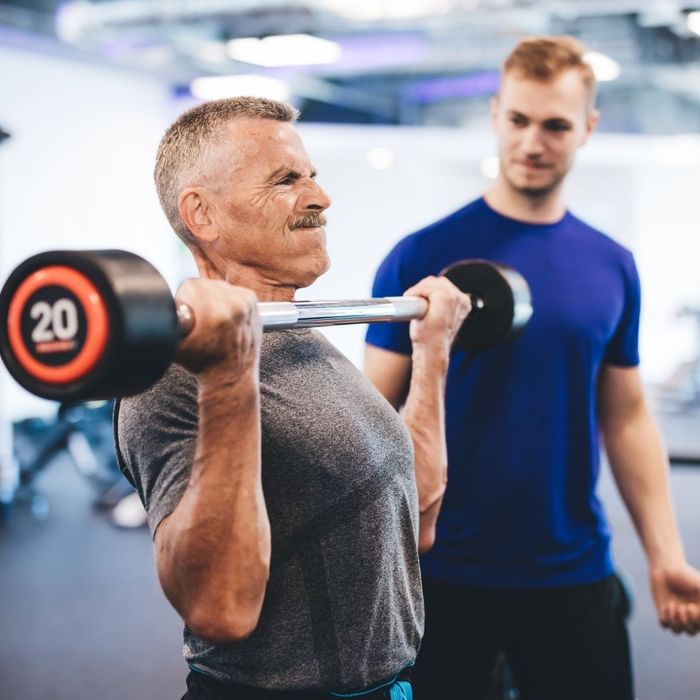 man lifting barbell with coach
