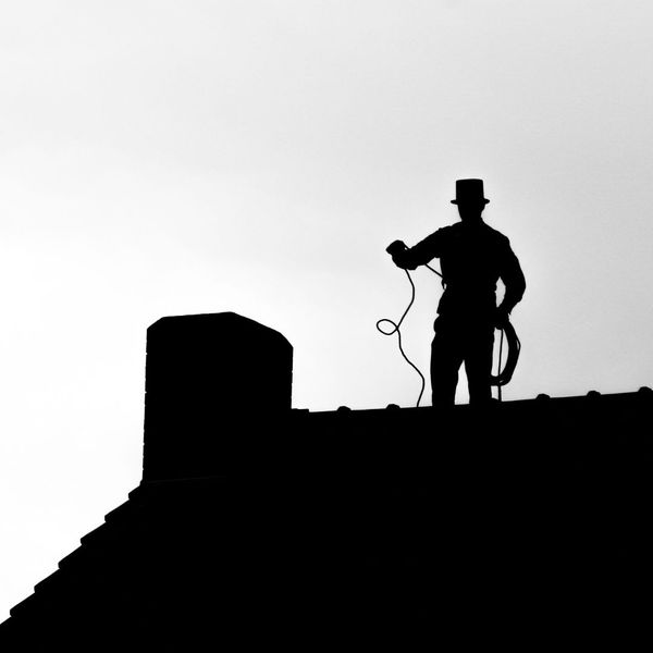 silhouette of a man working on a roof