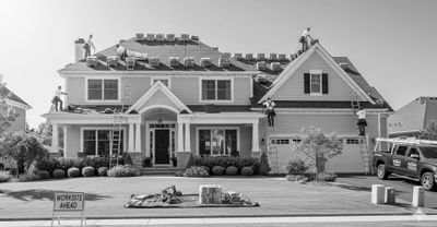 A team of professional roofers installing a new roof on a suburban house.