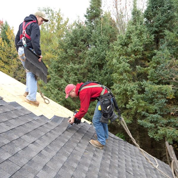 Roofer adding shingles