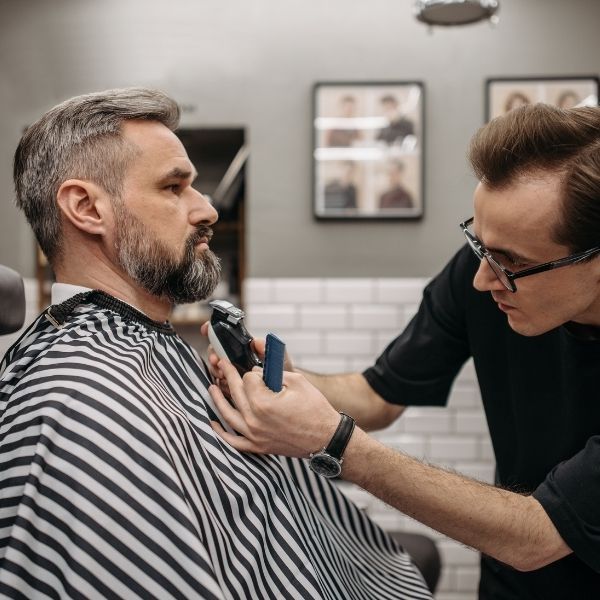 barber using clippers on a man's beard