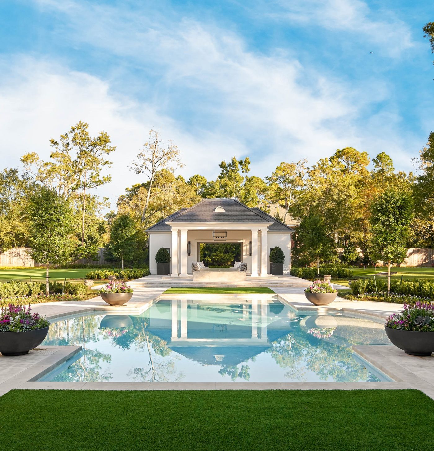 The custom-designed pool sits perfectly aligned with the main residence and pool house, creating a striking visual axis that defines the outdoor environment. Custom Luxury Pool Design in Piney Point Village, Houston