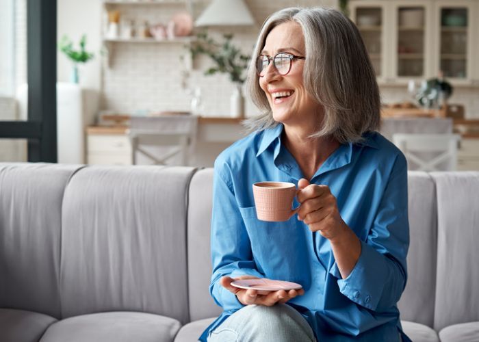 Person holding a pink mug while sitting on a couch