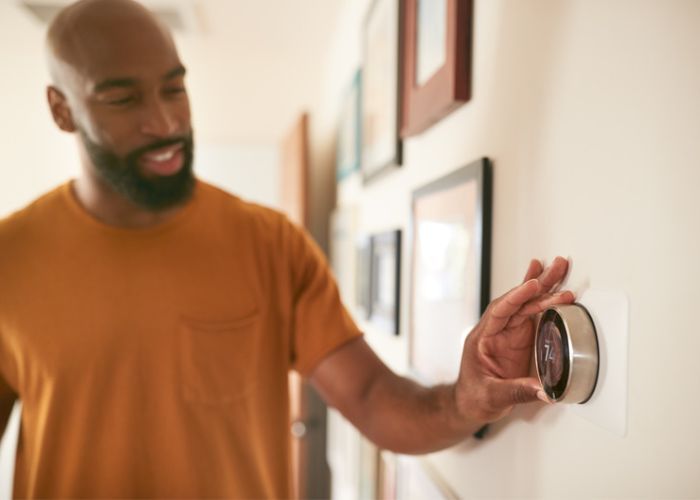 Person adjusting wall mounted thermostat