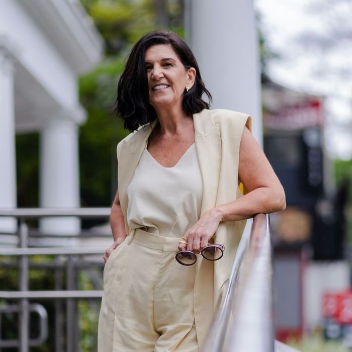 A confident woman in a chic cream outfit standing outdoors, representing holistic wellness and lifestyle.