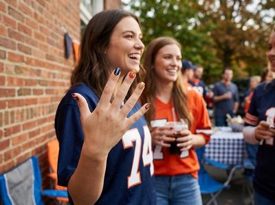 Woman showing team spirit with custom nail art at a tailgate