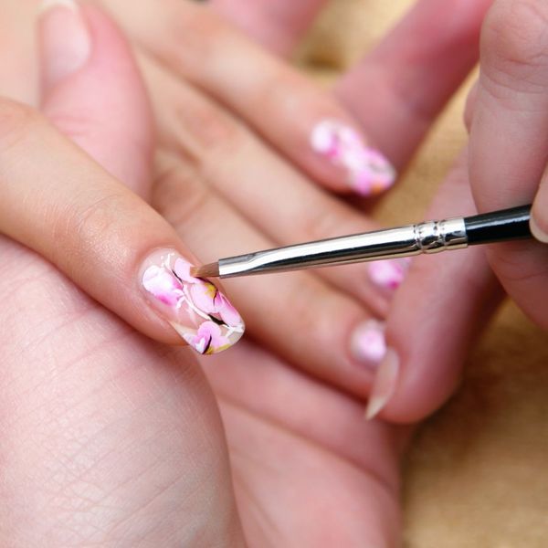 nail artist painting flowers on nails