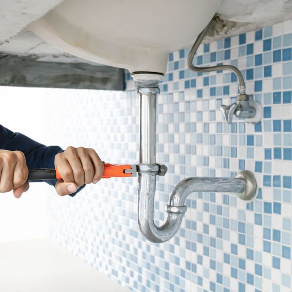 person using a wrench to loosen a pipe