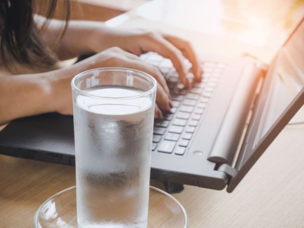 glass of water next to open laptop