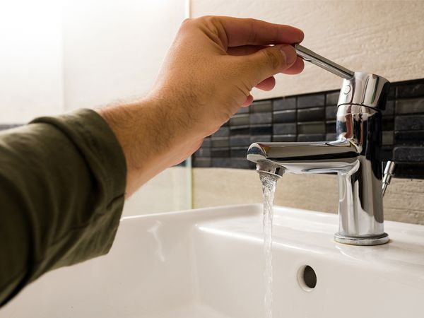 Man turning on sink tap