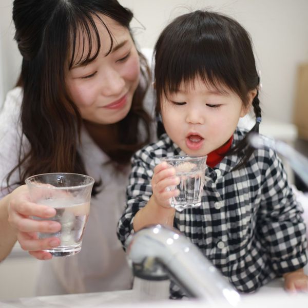 mother helping daughter with a glass of water