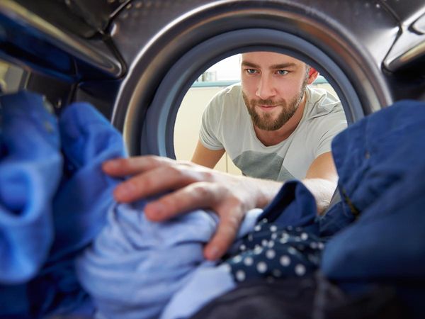 Smiling man reaching in and grabbing laundry out of a washing machine