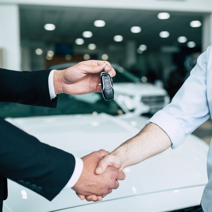 car salesman handing keys over to a buyer