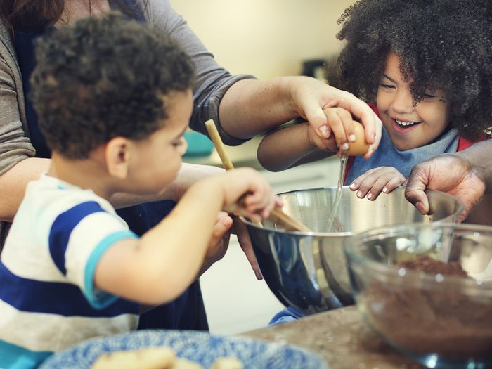 Two kids having fun cooking with their parents Two kids having fun cooking with their parents