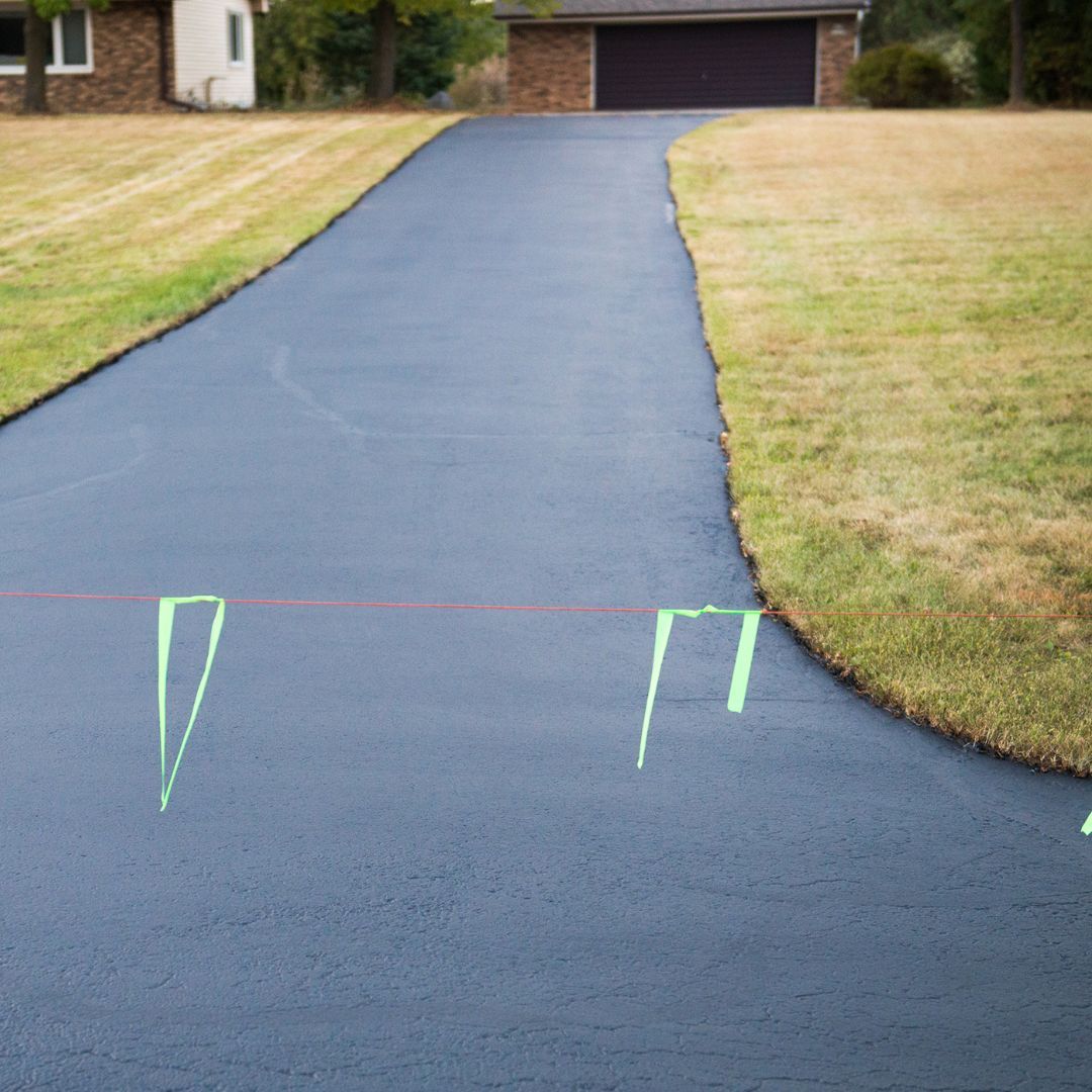 a smooth, new blacktop driveway, showcasing enhanced curb appeal after a replacement.