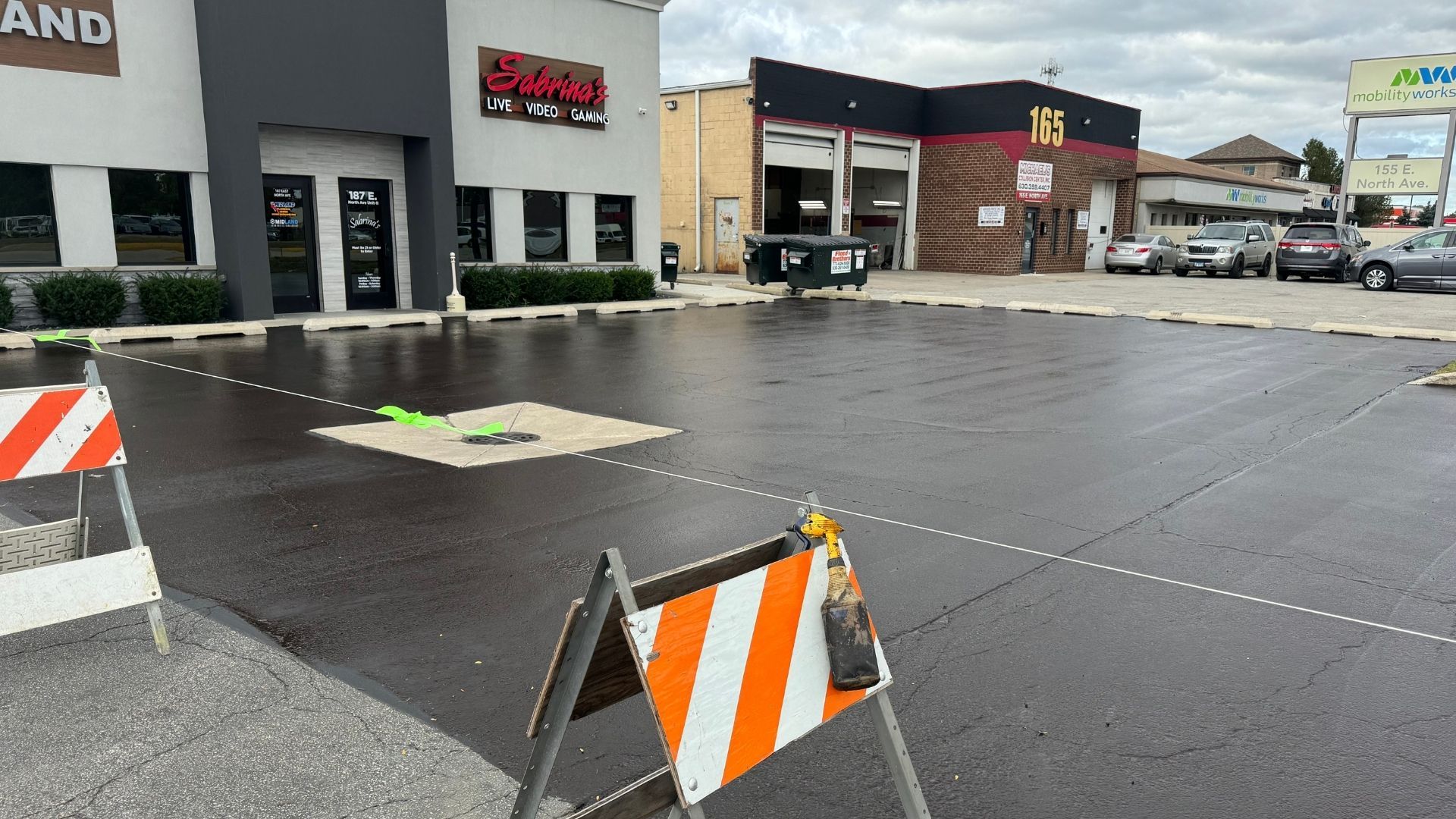 Newly paved parking lot with a barricade in the foreground.