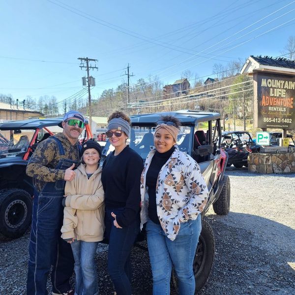 Family of four posing in front of UTV