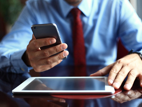 Business sitting at a table with a tablet on it and holding a mobile phone Business sitting at a table with a tablet on it and holding a mobile phone