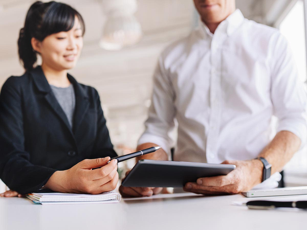Two business people talking and looking at a tablet Two business people talking and looking at a tablet