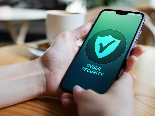 Person holding mobile phone that says Cyber Security on the screen with a shield and checkmark Person holding mobile phone that says Cyber Security on the screen with a shield and checkmark