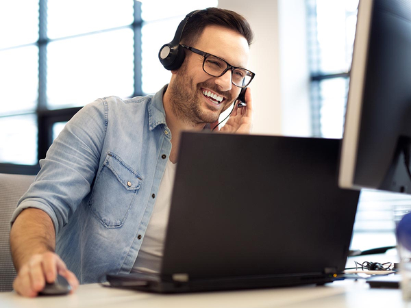 Smiling man using computer and talking on headset