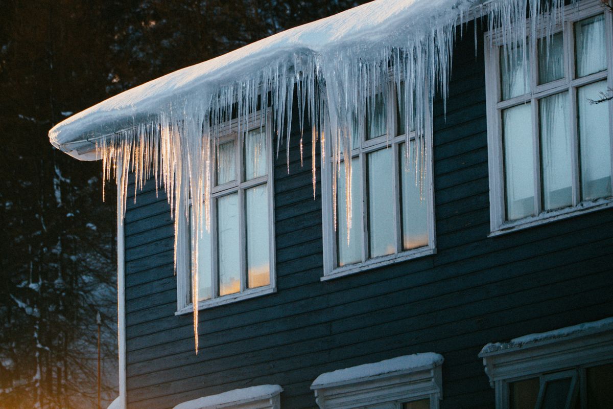 Heavy ice dam and icicles forming on the eaves of a residential roof