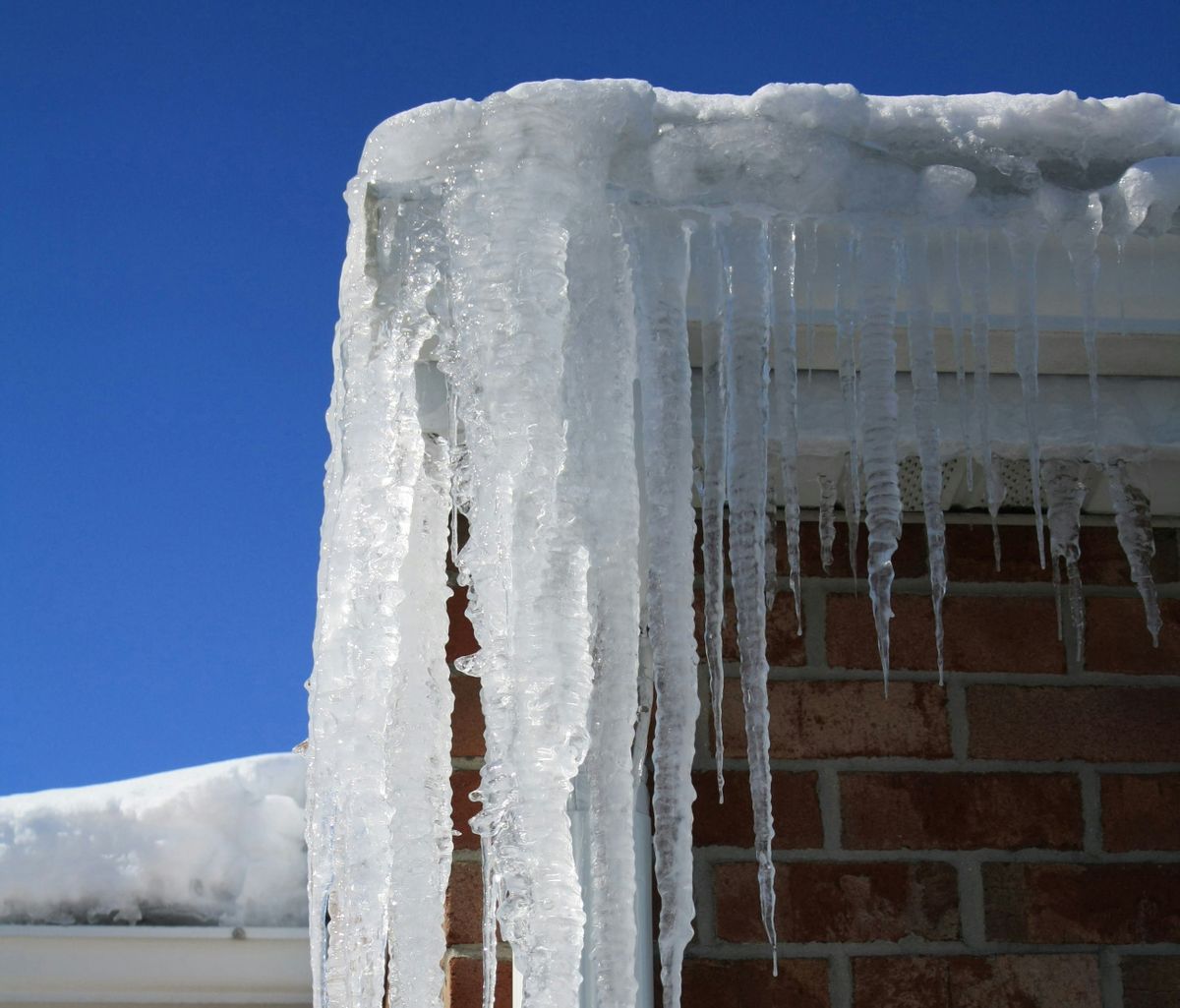 Ice dam backup under roof shingles along a residential eave line