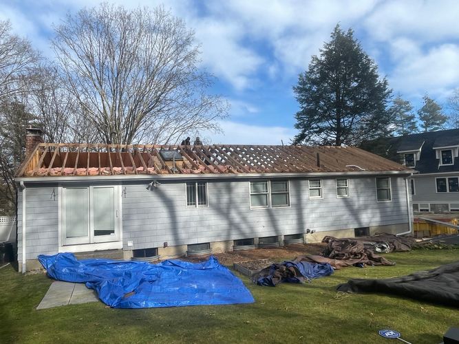 Residential roof stripped down to the open framing rafters and studs during a structural decking replacement project in Wellesley MA.