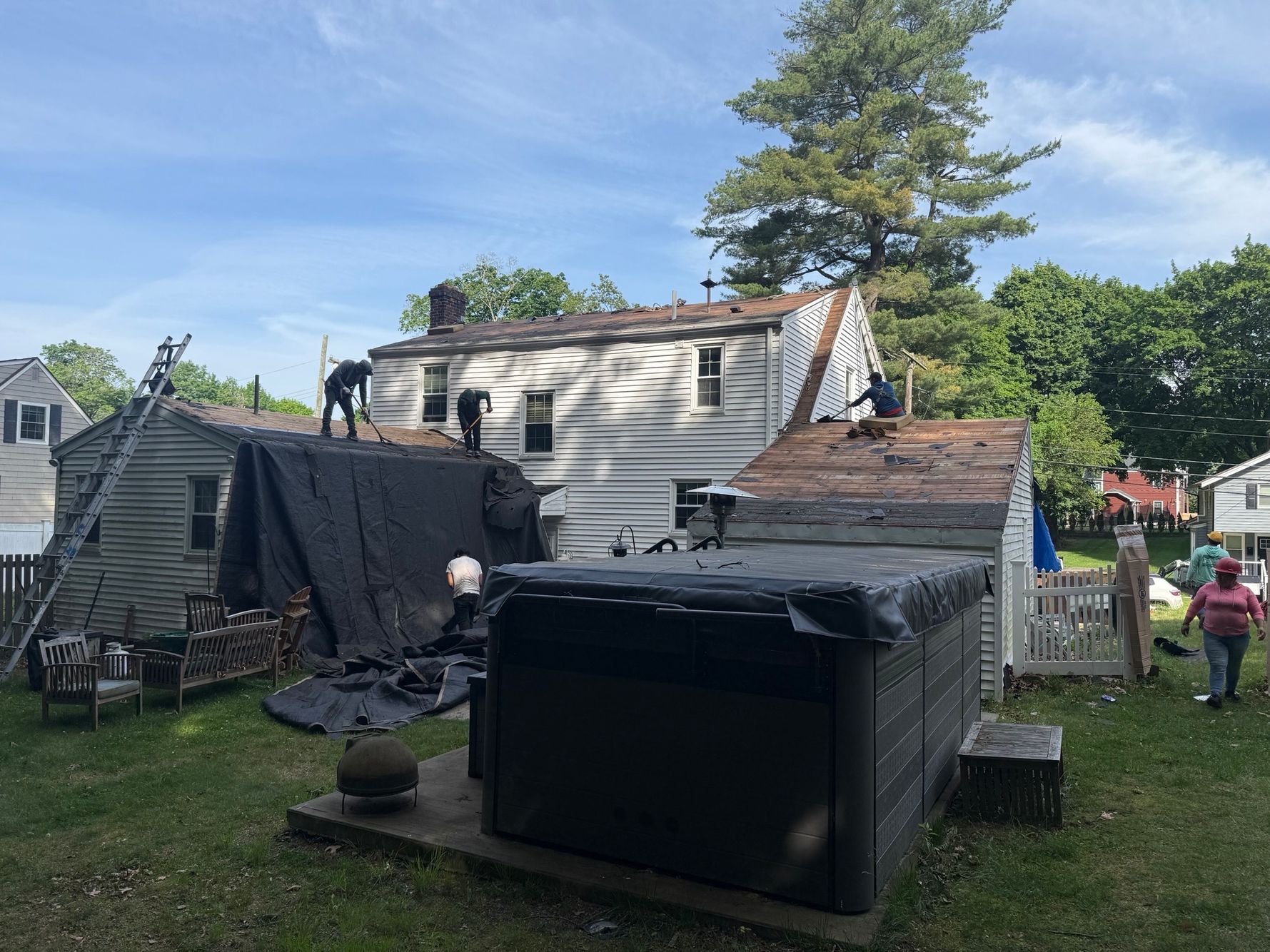 licensed roofing contractor rolling out synthetic underlayment over the roof deck as part of a complete re-roof installation in Natick, Massachusetts. Roofing crew inspecting and replacing damaged roof decking boards before new shingles are installed on a home in Natick, Massachusetts.