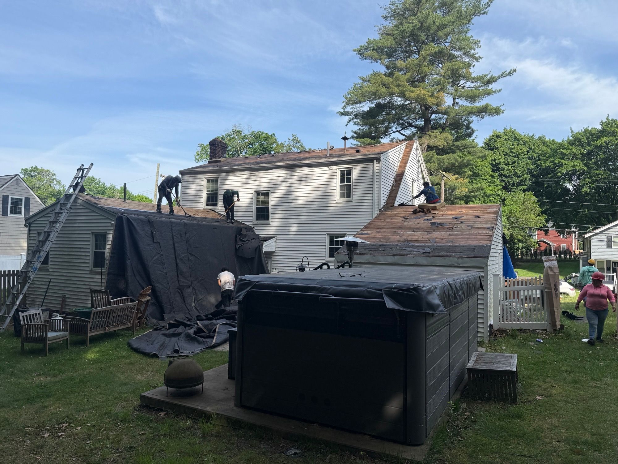 Roofing crew inspecting and replacing damaged roof decking boards before new shingles are installed on a home in Natick, Massachusetts.