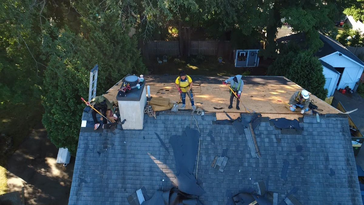 Aerial drone view of a asphalt shingle roof replacement with roof decking inspection in progress by Natarelli & Son Roofing and Gutters in Natick, MA.