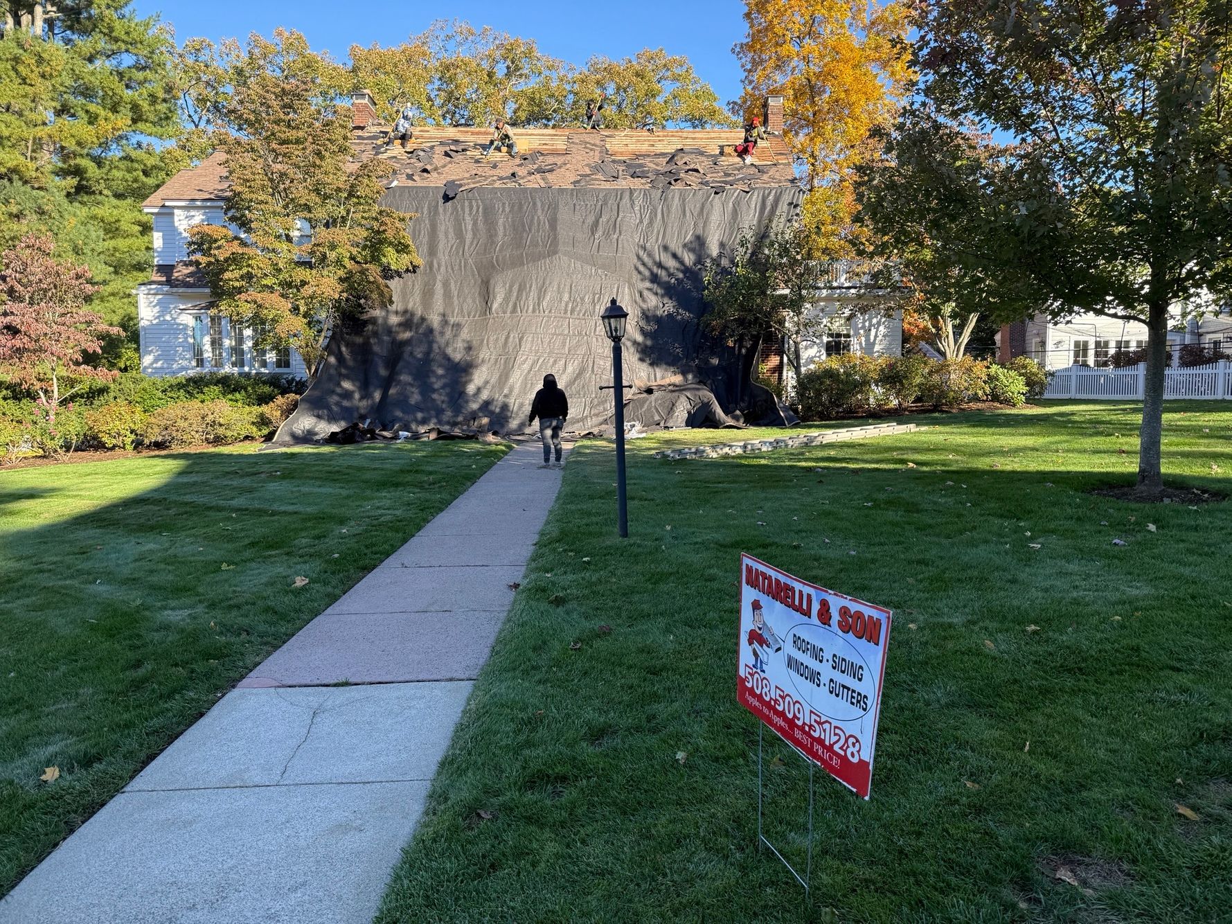 Heavy duty protective tarps systematically draped over landscaping and siding to shield a Wellesley property prior to a roof tear-off.