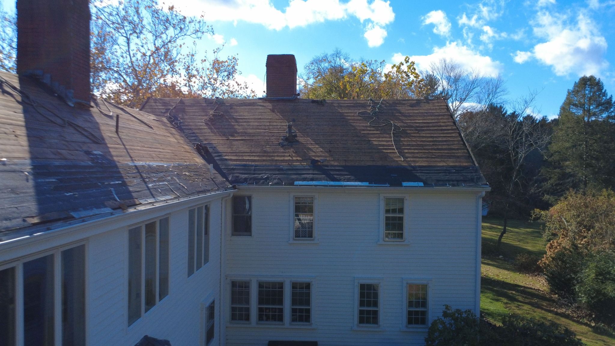 Rear drone view of Roofing work in progress on the historic Samuel Dunton House in Norfolk, Massachusetts Closeup of Roofing work in progress on the historic Samuel Dunton House in Norfolk, Massachusetts
